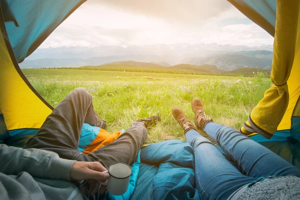 산맥의 전망과 텐트에 누워 있는 두 사람. 알타이, 러시아. 스톡 사진