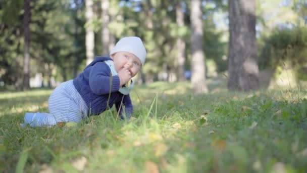 Bébé rampe sur l'herbe et mange des feuilles, souriant et jouant 