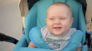 Stoller içinde oturan ve gülümseyen iki diş bebekle. Park, açık.