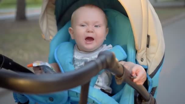 The kid rides in a carriage and waving hands of the packages with baby food in their hands. — Stock Video