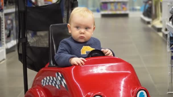 Baby sitting in the shopping cart in a store. — Stock Video