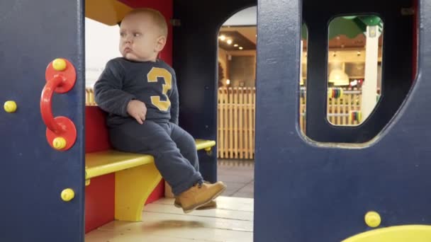 Baby jongetje spelen in een klein huisje op speelplaats. — Stockvideo