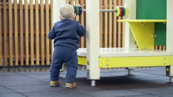 Ein kleiner Junge versucht, in ein Haus auf dem Spielplatz zu klettern. — Stockvideo