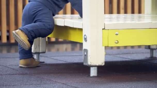 Een kleine jongen probeert te klimmen in huis op de speelplaats. Close-up van de benen. — Stockvideo