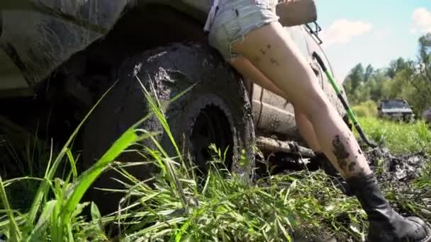 Dívka vedle špinavé terénní auto v lese. Kamera se pohybuje nahoru a dolů. — Stock video