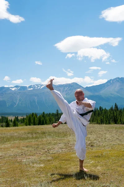 Adam beyaz kimono ve dağ zemin üzerine siyah kuşak eğitim karate.