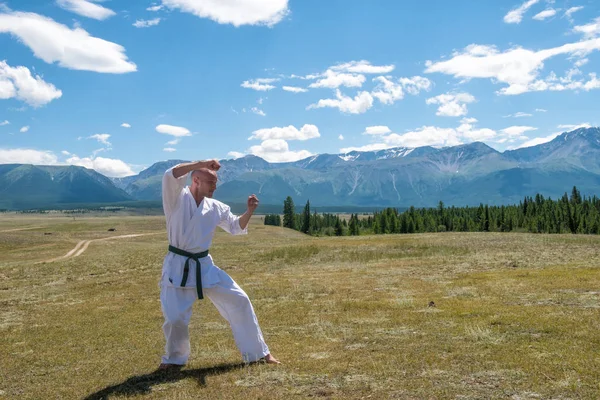 Adam beyaz kimono ve dağ zemin üzerine siyah kuşak eğitim karate.
