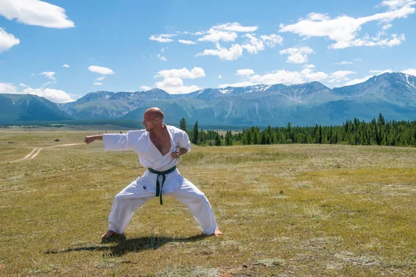 Adam beyaz kimono ve dağ zemin üzerine siyah kuşak eğitim karate.