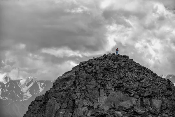 Silhouette eines Mädchens mit Rucksack auf einem riesigen Berg. Sehr weit. episches Schwarz-Weiß-Foto. lizenzfreie Stockbilder