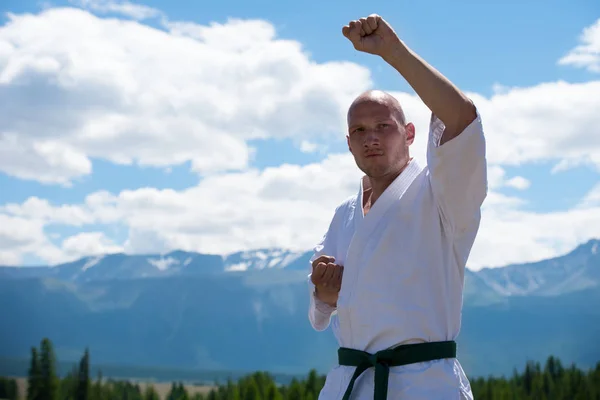 Adam beyaz kimono ve kara kuşak eğitimi kung-fu, karate veya dağ zemin üzerine aikido.