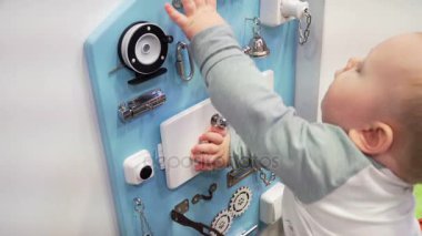 Dikkatle duvardaki meşgul yönetim kurulu ile oynarken küçük oğlu. Yakın çekim.