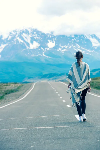 Schönes einsames Mädchen, das die Straße entlang geht. in der Ferne, Berge. altai, russland. lizenzfreie Stockfotos