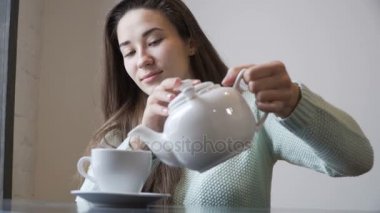 Kadın bir demlik çay bir fincan içine dökülen. Kafede