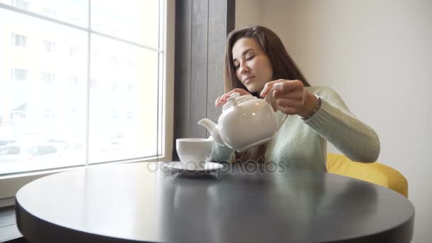 Frau gießt Tee aus Teekanne in Tasse. — Stockvideo