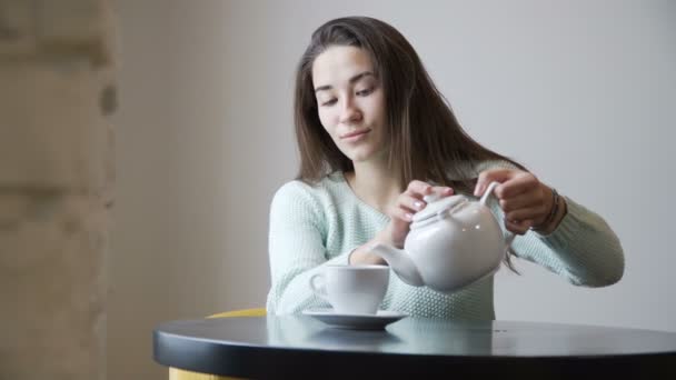 stock video Woman pours tea from a teapot into a cup. In cafe.