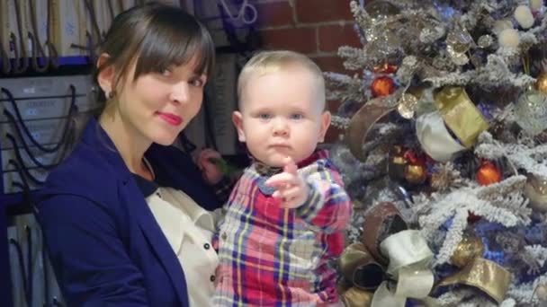 Mãe com seu bebê nos braços ao lado de uma árvore de Natal. Ano Novo 2017 . — Vídeo de Stock