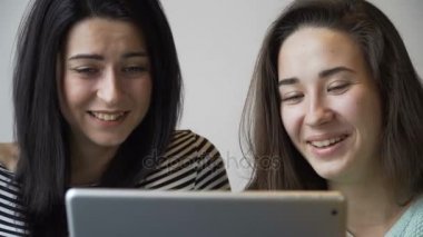 Bir tablet Pc ve gülmek kafede oturan iki güzel kız arıyor. Yakın çekim.
