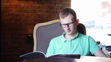 Kafede oturan menüyü okuyan genç adam