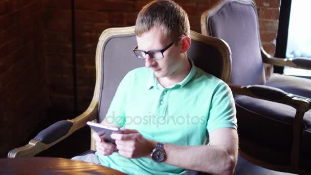 Молодой человек с помощью смартфона сидит в кафе в городе — стоковое видео