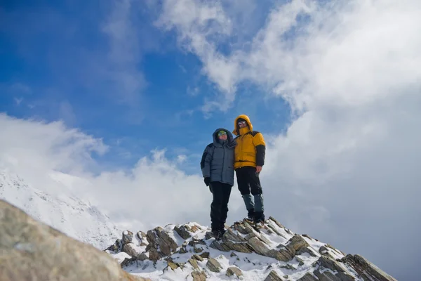 O casal homem e mulher em pé no topo de uma montanha nevada — Fotografia de Stock