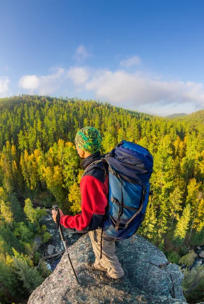 Man met rugzak en trekking pole in bandana staande op een roc — Stockfoto