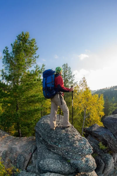 Man met rugzak en trekking pole in bandana staande op een roc — Stockfoto