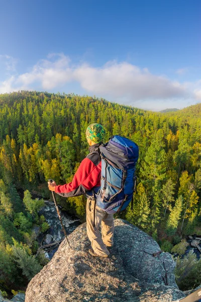 Man met rugzak en trekking pole in bandana staande op een roc — Stockfoto