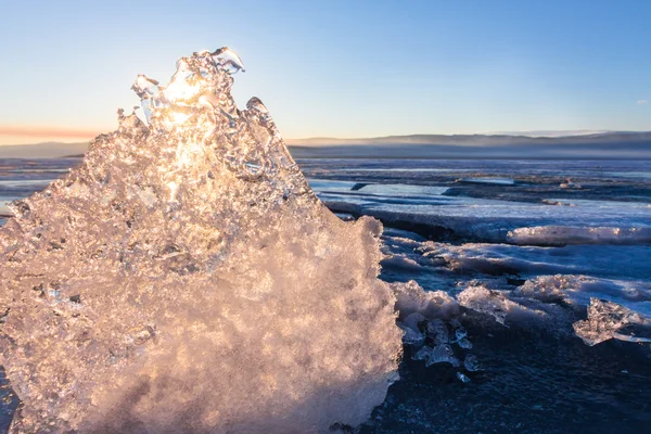 氷の透明なテクスチャを通して輝く夕暮れ時の太陽 — ストック写真