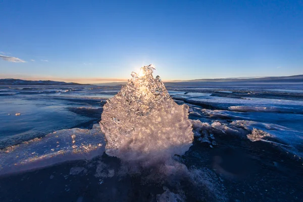 氷の透明なテクスチャを通して輝く夕暮れ時の太陽 — ストック写真