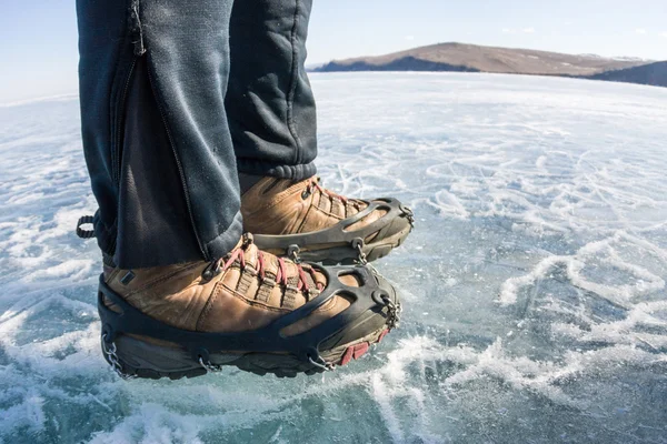 Human legs in hiking boot in ice crampons on the texture Baikal Royalty Free Stock Photos