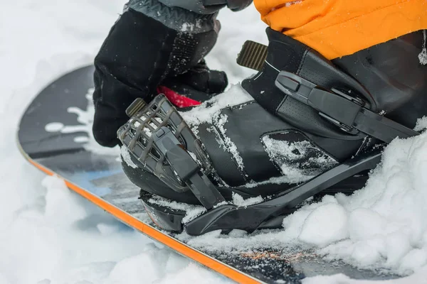 L'homme en bottes noires boutons fixation snowboard . — Photo