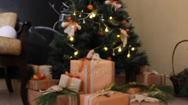 Hediyeler oyuncak ve beyaz ışık garland göz kırpıyor ile dekore edilmiş Noel köknar ağacı altındaki kutuları sunar. Slayt kamera hareketi.