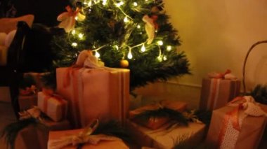 Hediyeler oyuncak ve beyaz ışık garland göz kırpıyor ile dekore edilmiş Noel köknar ağacı altındaki kutuları sunar. Slayt kamera hareketi.