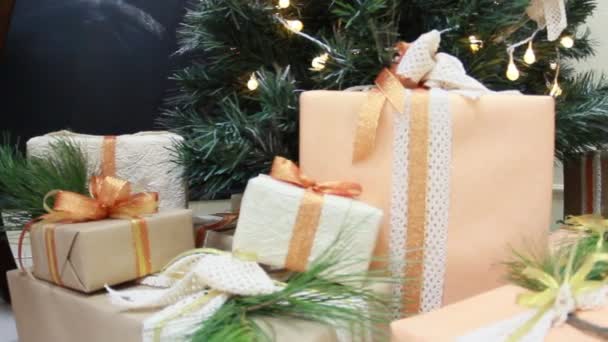 Regalos presenta cajas bajo abeto navideño decorado con juguetes y guirnalda guiñada blanca. Movimiento de cámara deslizante . — Vídeos de Stock