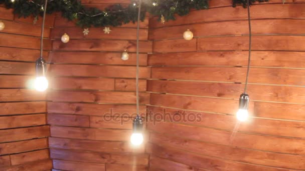 Cámara deslizante. Luces ardientes en cables sobre un fondo de madera con bolas y oropel — Vídeos de Stock