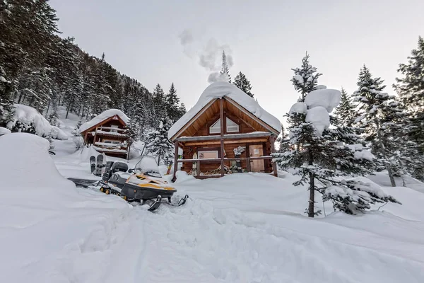 Snowmobile de chalés de casa em floresta de inverno com neve em moun — Fotografia de Stock