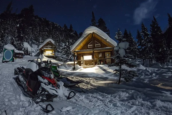 Moto de nieve de chalets de casa en el bosque de invierno con nieve en ligh — Foto de Stock