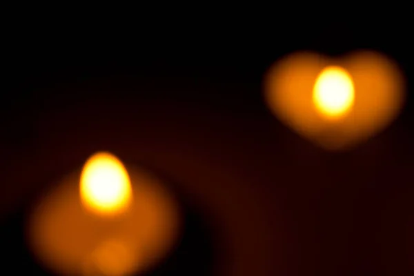La pequeña vela redonda con un comprimido en forma de corazón se enciende en la oscuridad —  Fotos de Stock