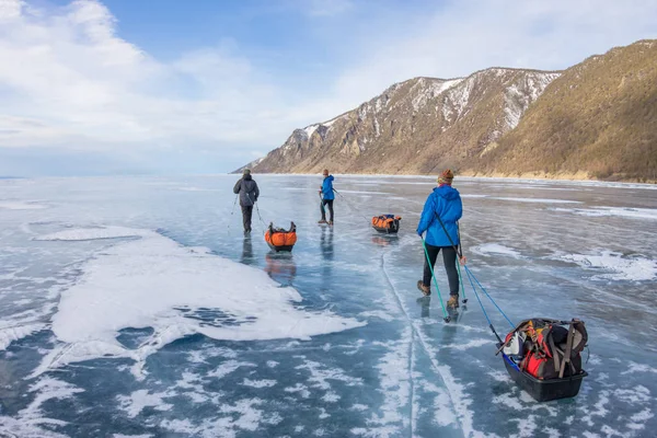 女人和一个男人与一个雪橇和登山杖是贝加尔湖的冰 — 图库照片