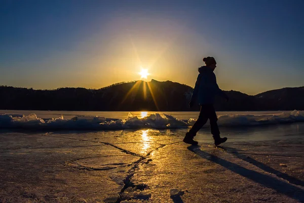 Girl is on the ice of Lake Baikal in the light of the setting su — Stock Photo, Image