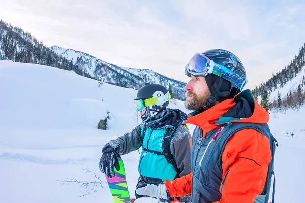 Freeriders esquiadores masculinos y snowboarders están en las montañas en —  Fotos de Stock