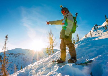 Freeride snowboard şafakta tepe üzerinde duruyor ve onun ha gösterir