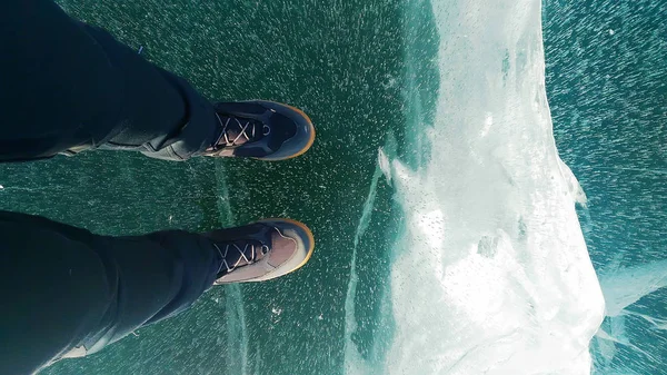 Patas femeninas en botas de cuero de pie sobre hielo agrietado, vista superior — Foto de Stock