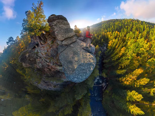 Backpacker bovenop een rots vallen bij zonsopgang. Groothoek luchtfoto panorama — Stockfoto