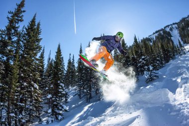 Snowboard freerider orman ve dağlar bir arka plan üzerinde bir kar rampa güneşin üzerinden atlama