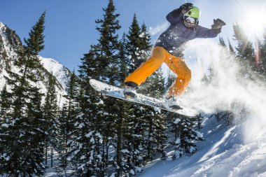 Snowboard freerider orman ve dağlar bir arka plan üzerinde bir kar rampa güneşin üzerinden atlama