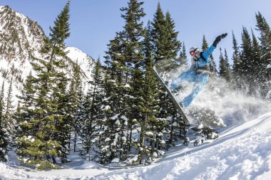 Snowboard freerider orman ve dağlar bir arka plan üzerinde bir kar rampa güneşin üzerinden atlama