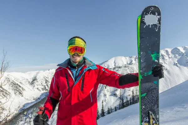 Portrét mladého muže lyžařské brýle držení lyží v horách — Stock fotografie