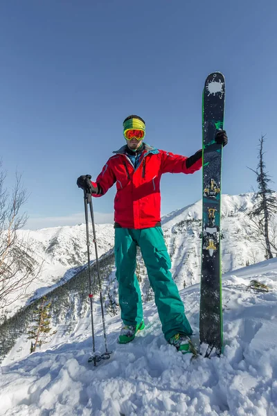 Portrait young man ski goggles holding ski in the mountains