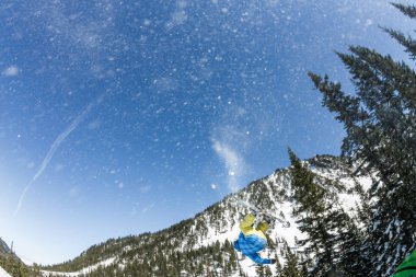 Snowboard freerider orman ve dağlar bir arka plan üzerinde bir kar rampa güneşin üzerinden atlama